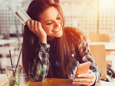 Young woman holding credit card and texting