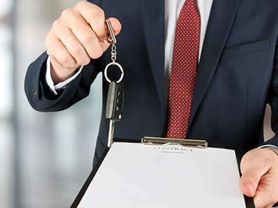 businessman offering a car key with contract.