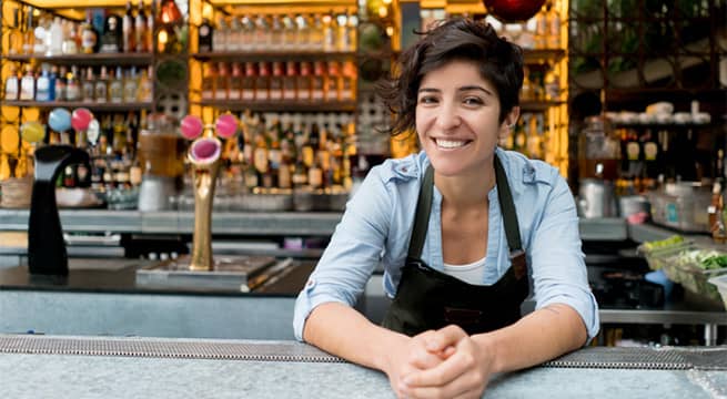 Woman bartender (bank customer) posing behind the bar for the picture