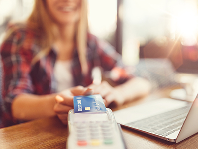 Woman checking rewards on laptop with debit card in hand
