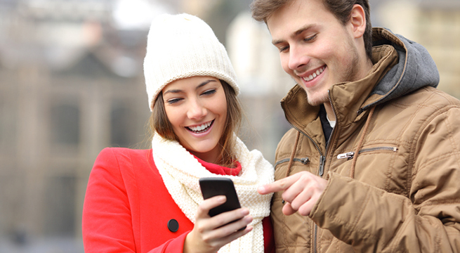 Couple consulting a smart phone in winter
